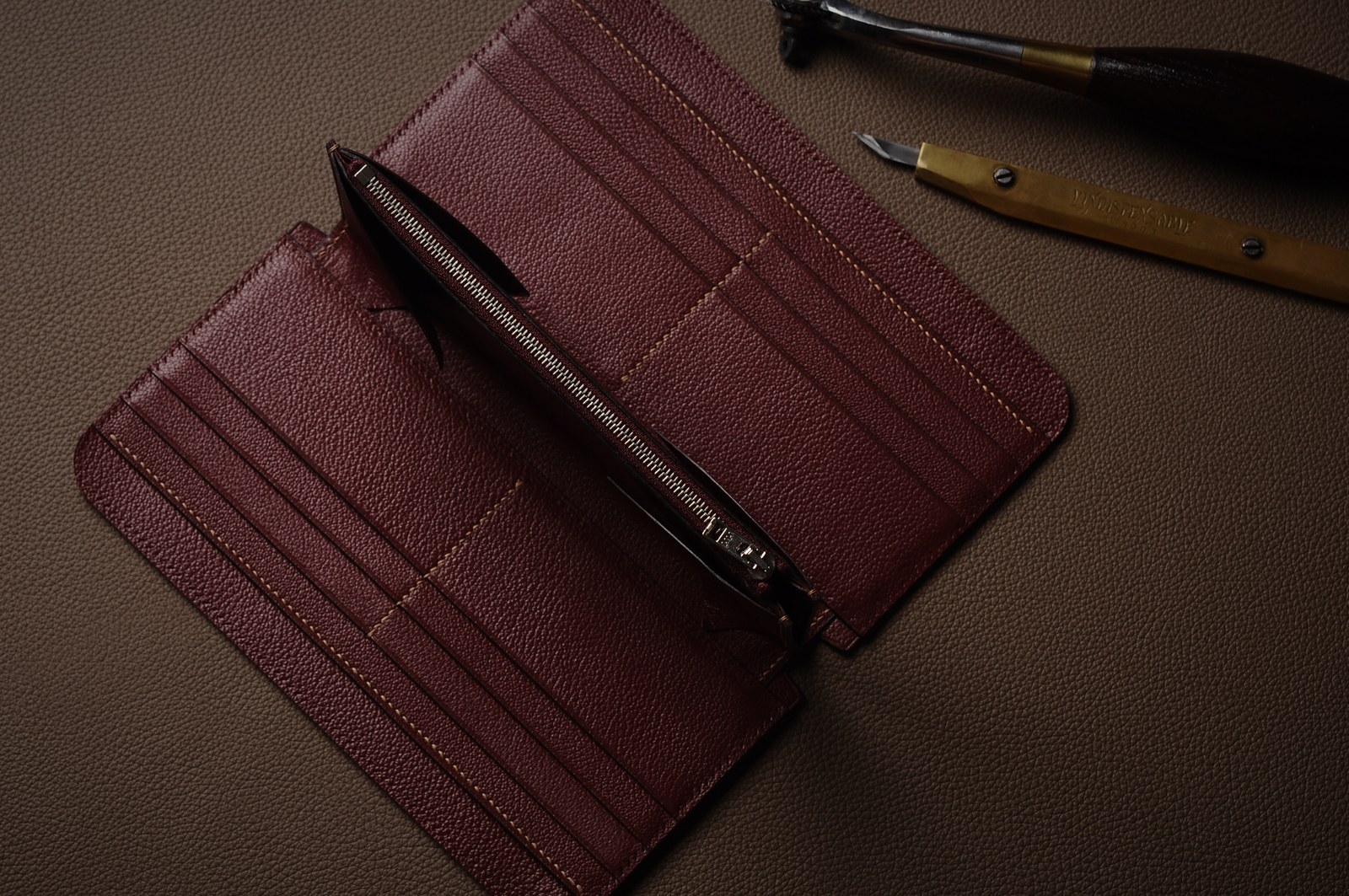 Open burgundy long wallet showing card slots, stitched edges and interior construction