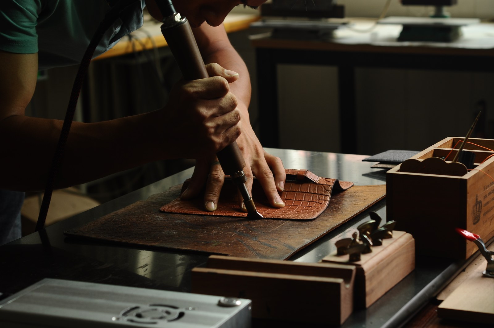 Hands using a manual press-cutting tool on brown leather components