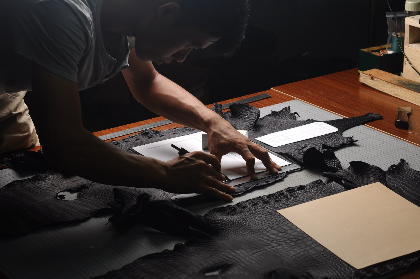 Two makers aligning and cutting dark leather panels at a workshop bench