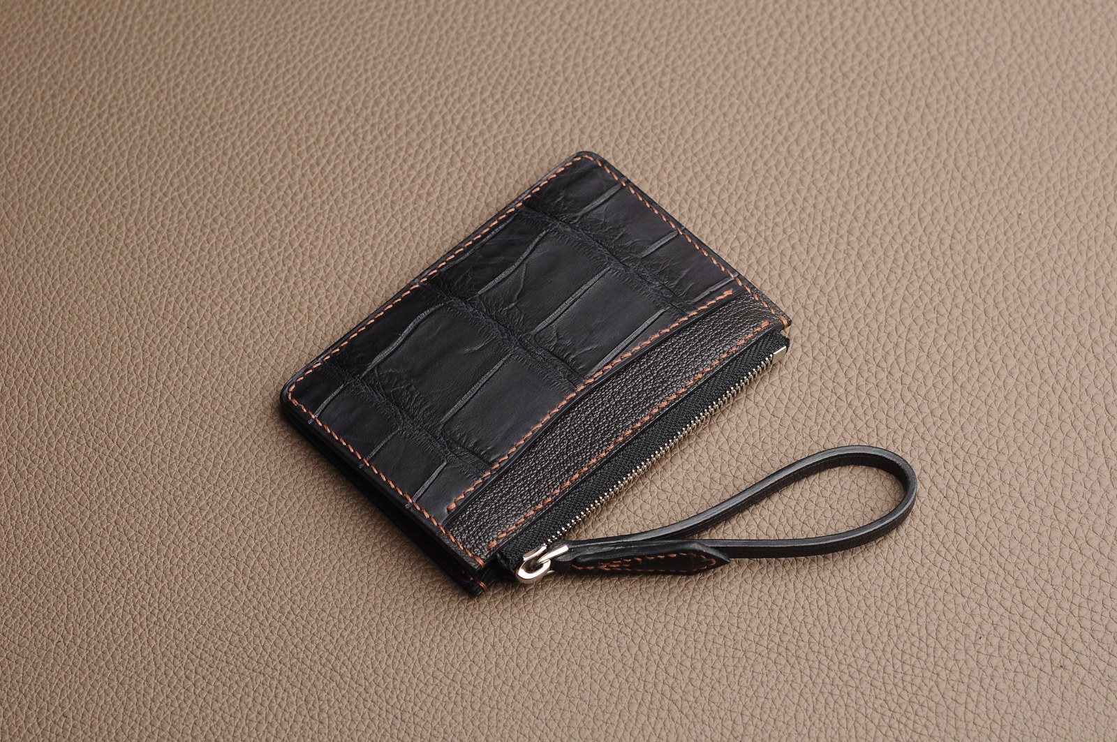 Closed black crocodile leather zip pouch with a wrist strap
