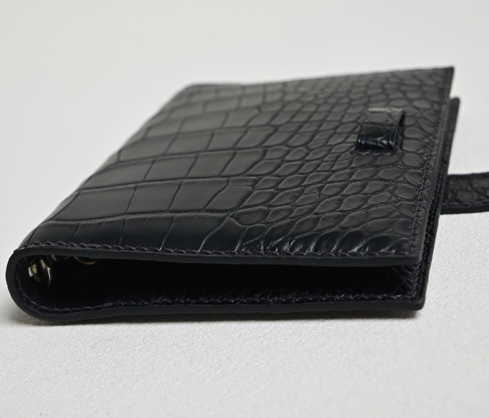 Closed black crocodile leather notebook cover on a white background