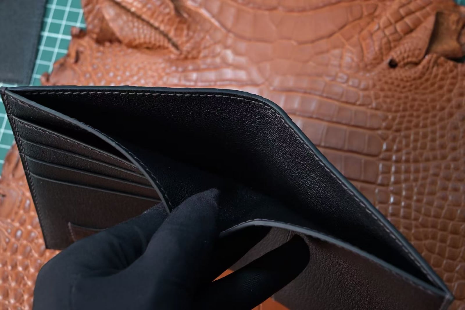 Gloved hands holding an open black passport cover with multiple card slots on the left and a large document pocket on the right
