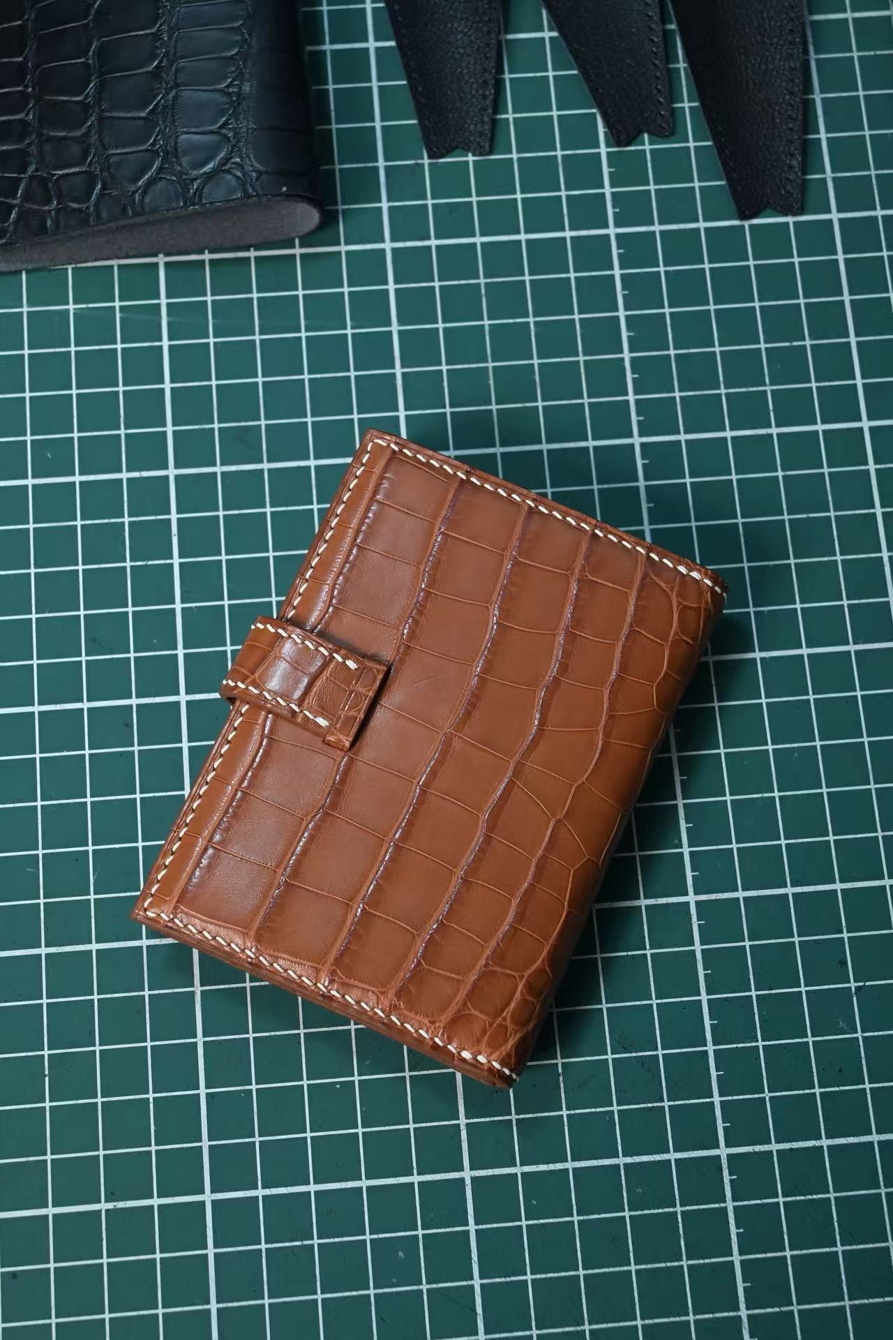 Closed brown crocodile leather coin purse on a green cutting mat