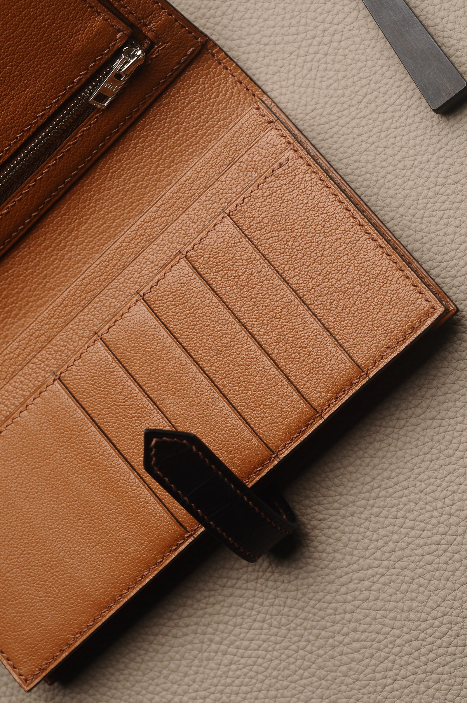 Tan wallet interior with card slots, a black closure strap and finished edges