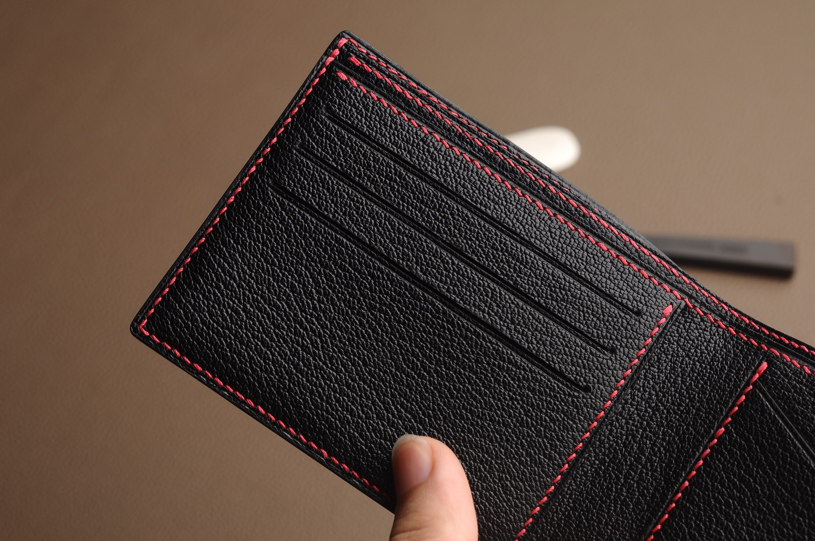 Black wallet card slots with red contrast stitching